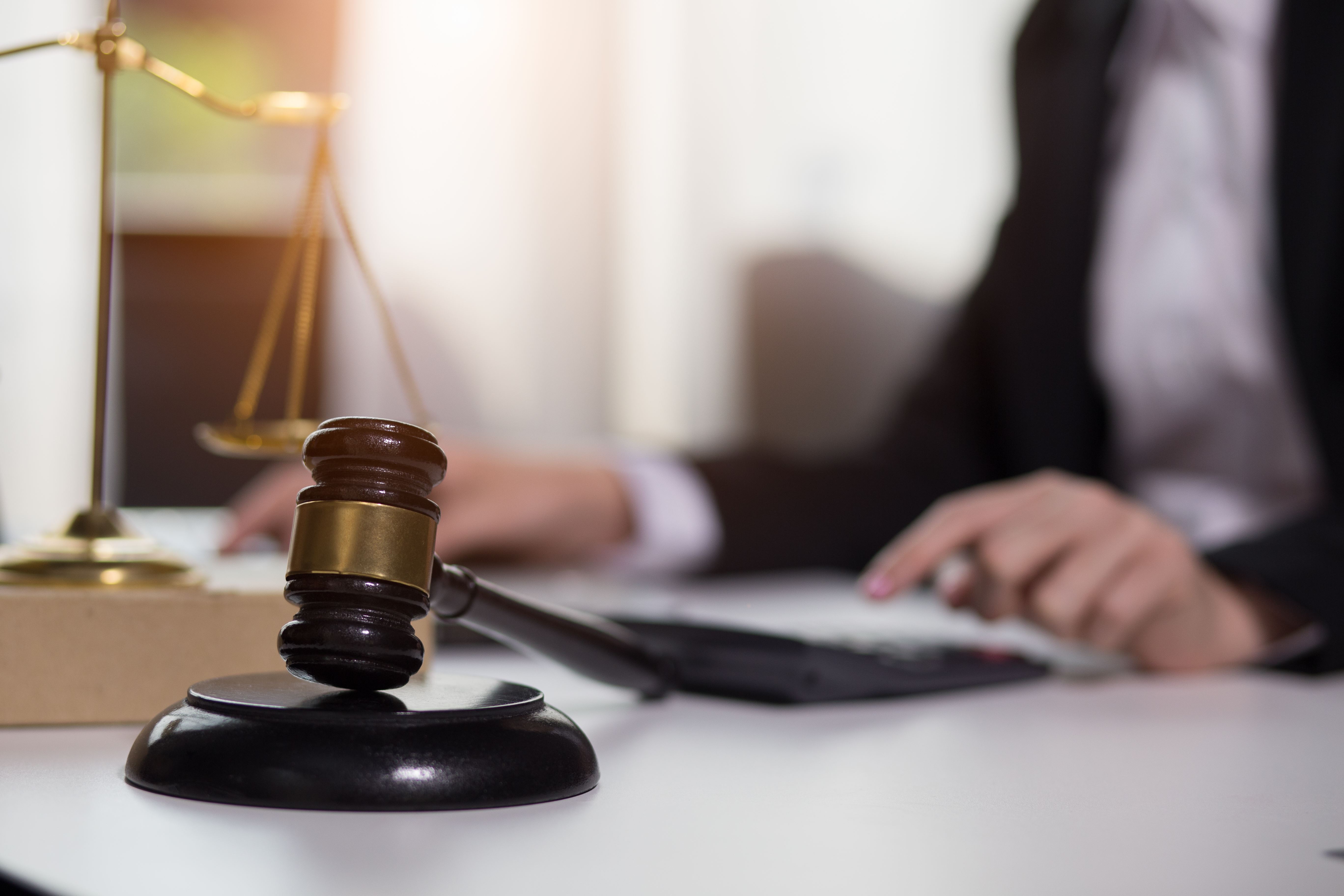 business person sitting at table behind gavel